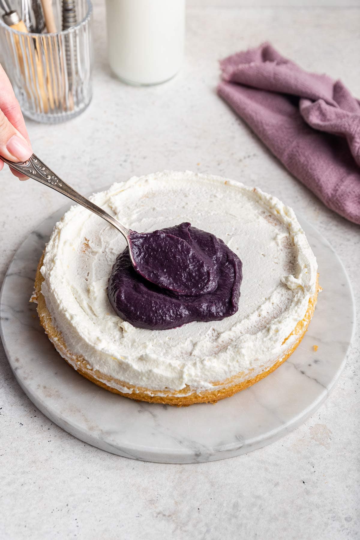 dolloping blueberry curd on top of a layer of cake