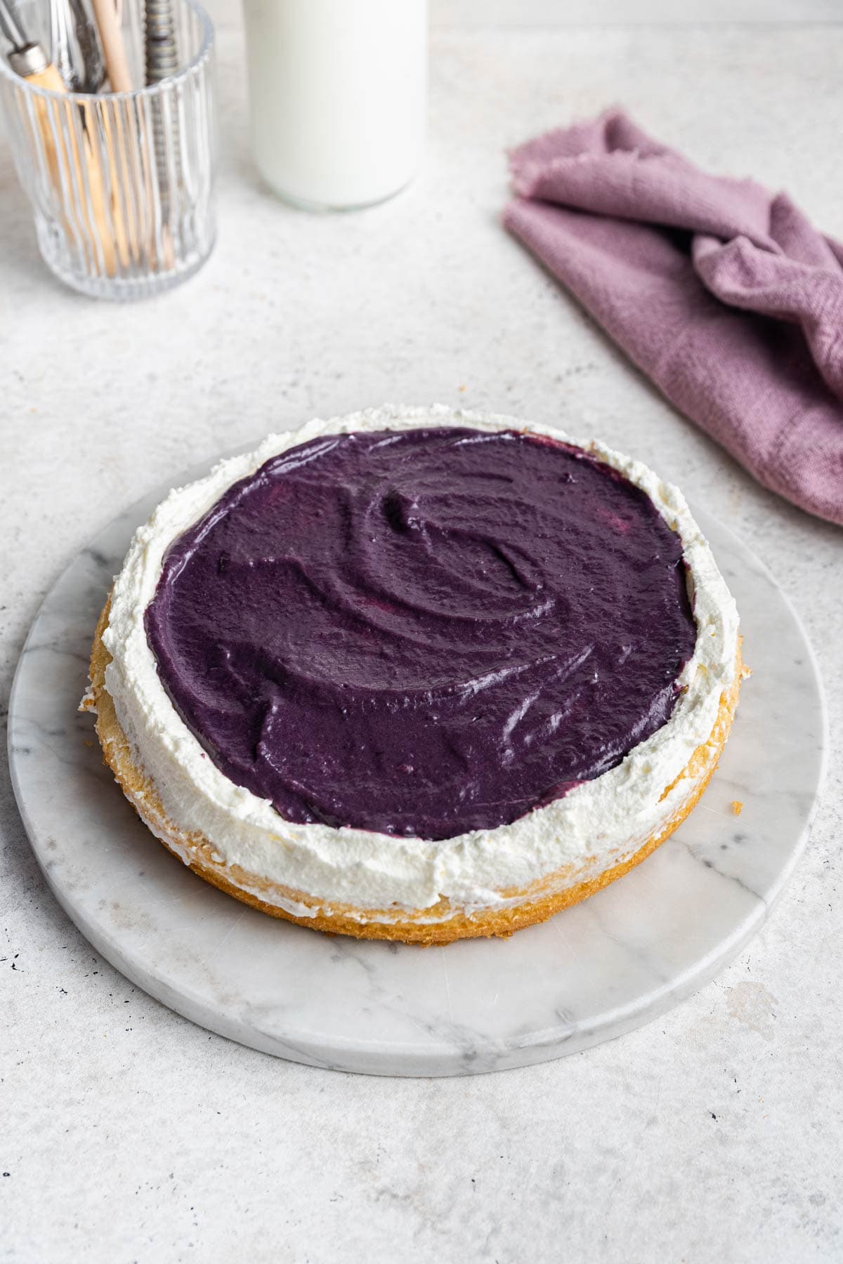 thick layer of blueberry cardamom curd spread on top of whipped cream frosting
