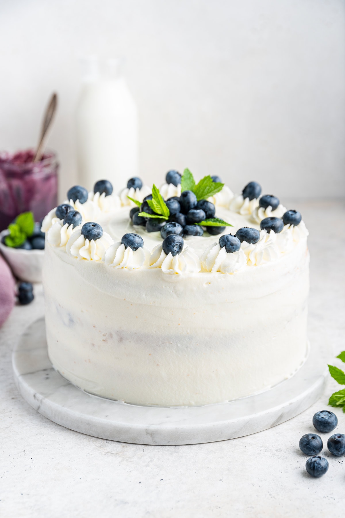 three layer blueberry cake covered with whipped cream frosting and decorated with blueberries