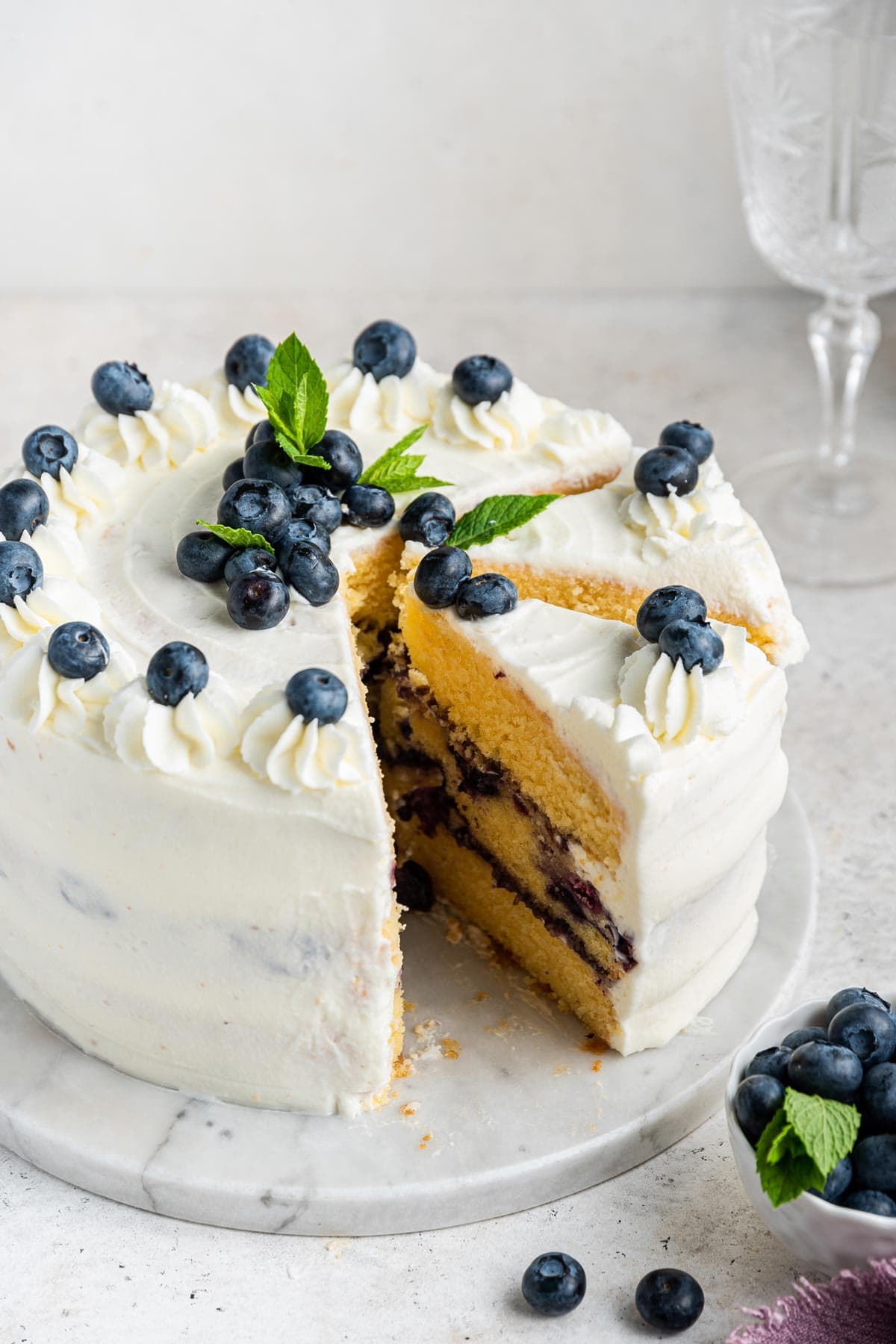 three layer vanilla cake filled with blueberry curd on a marble cake plate