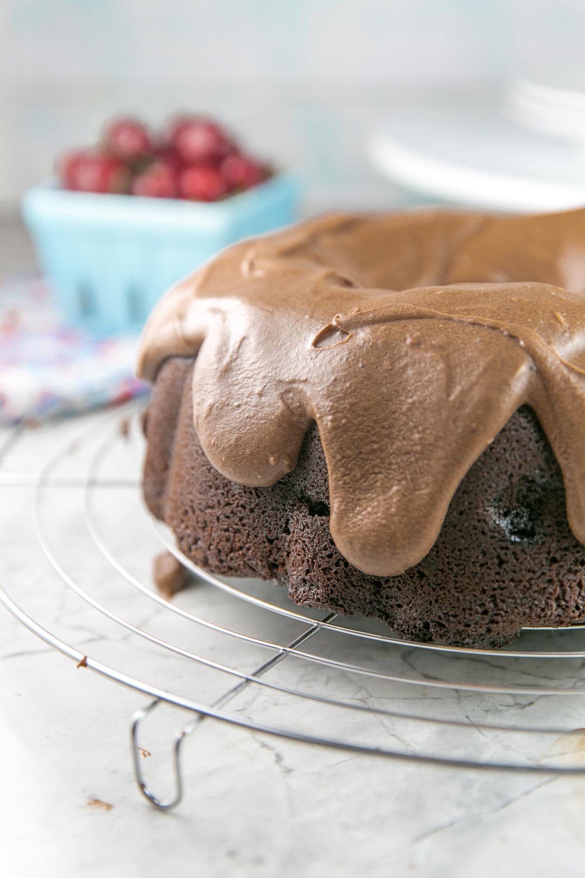 thick chocolate fudge frosting dripping over the sides of a chocolate cherry bundt cake