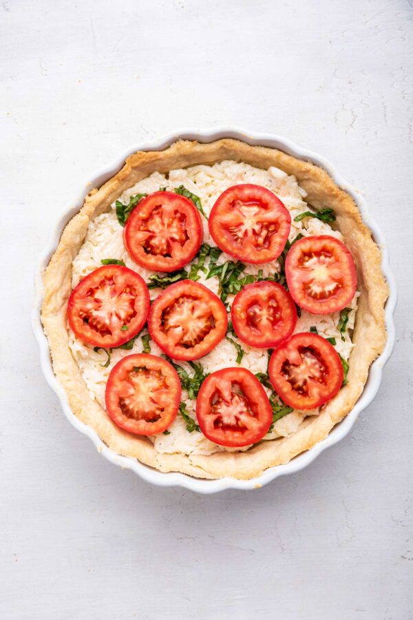 slices of fresh tomatoes piled on an unbaked tomato pie
