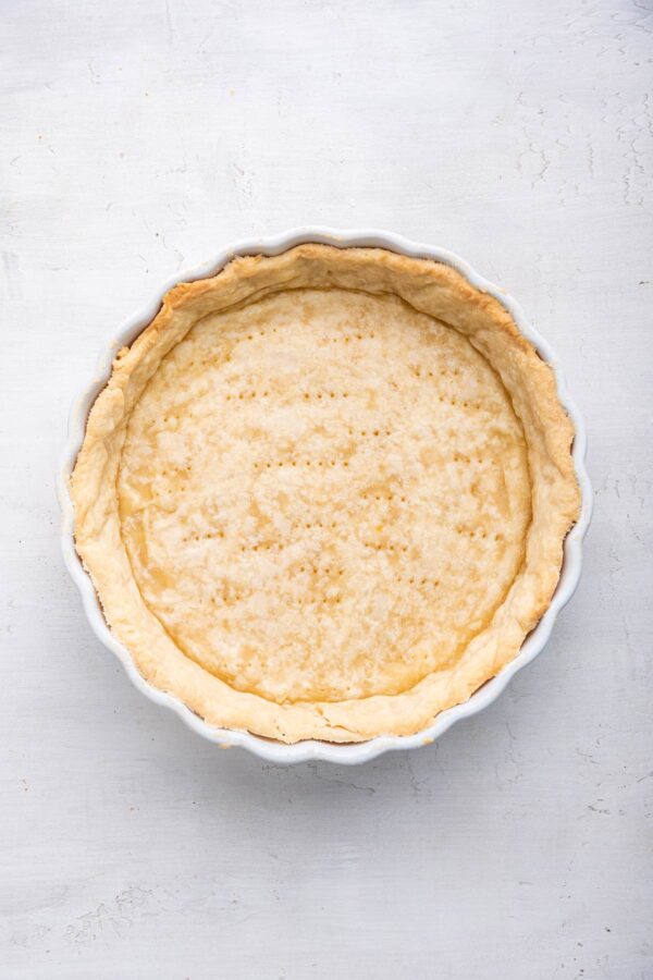 parbaked pie crust in a white ceramic pie plate