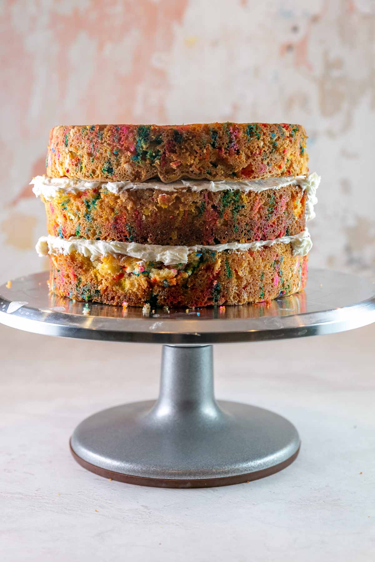 three layers of cake stacked on a cake stand waiting to be frosted