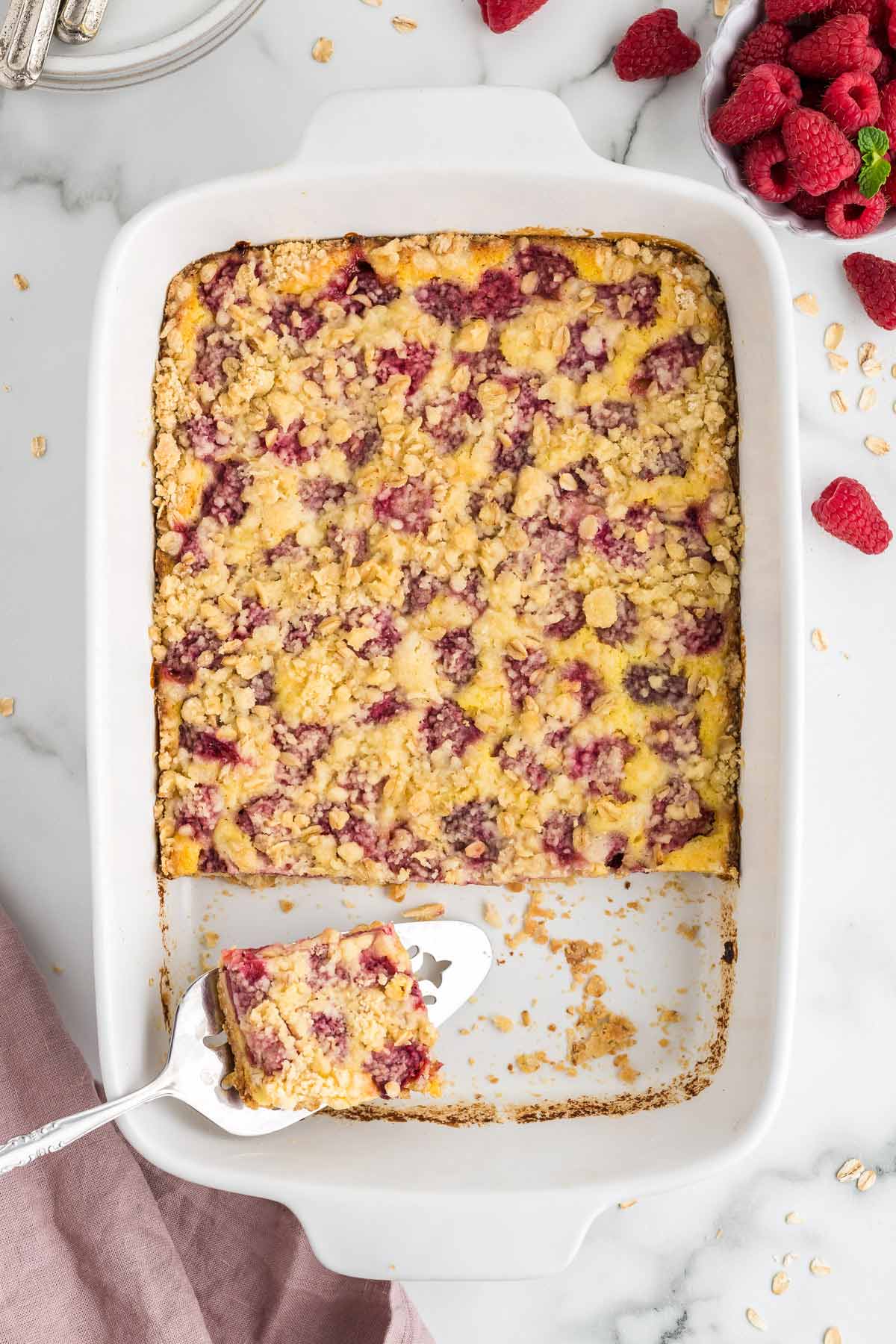 Raspberry pie bars after being baked with a spatula taking one bar from the dish. 