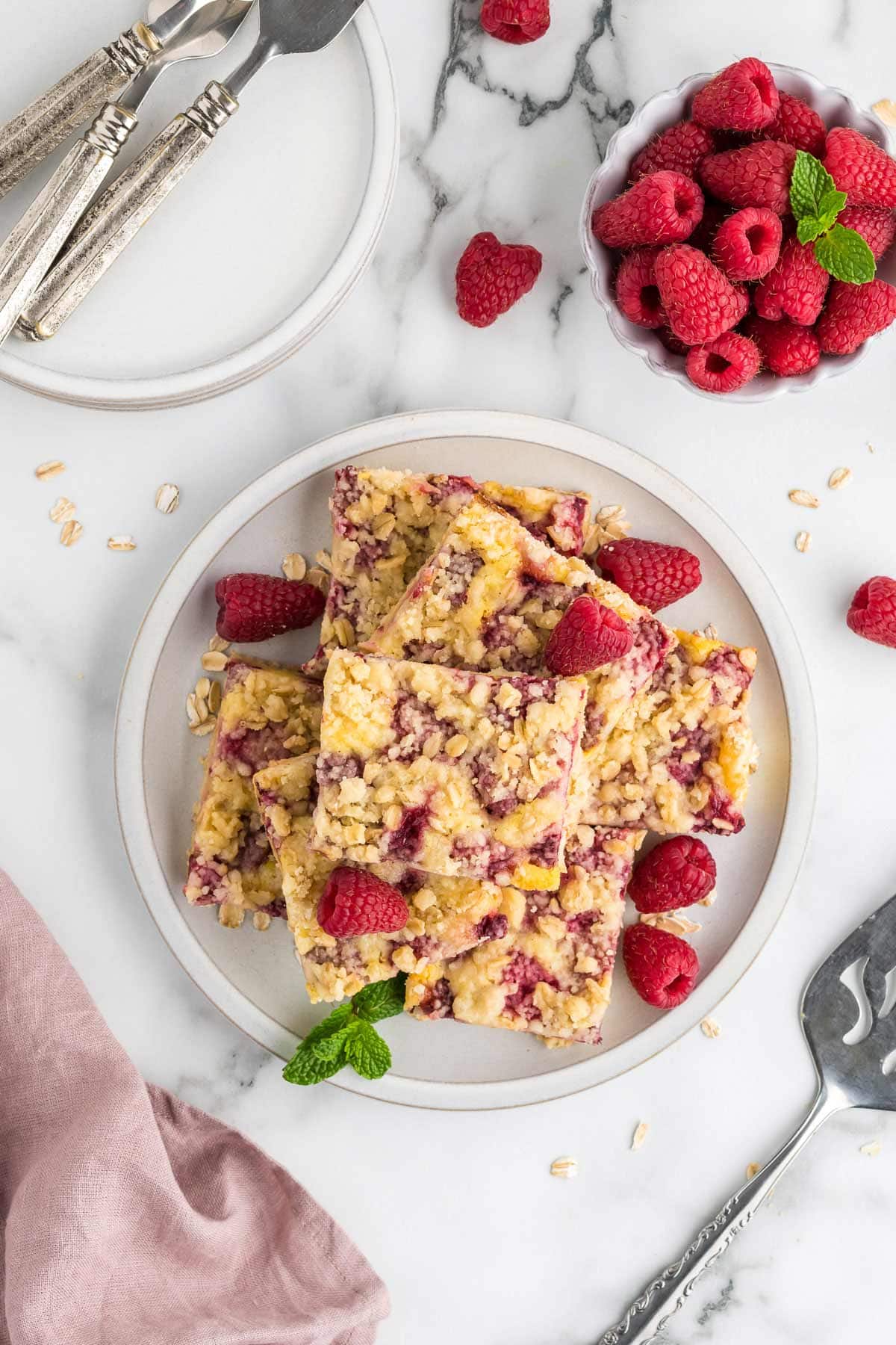 Overhead shot of raspberry pie bars stacked on a white plate.