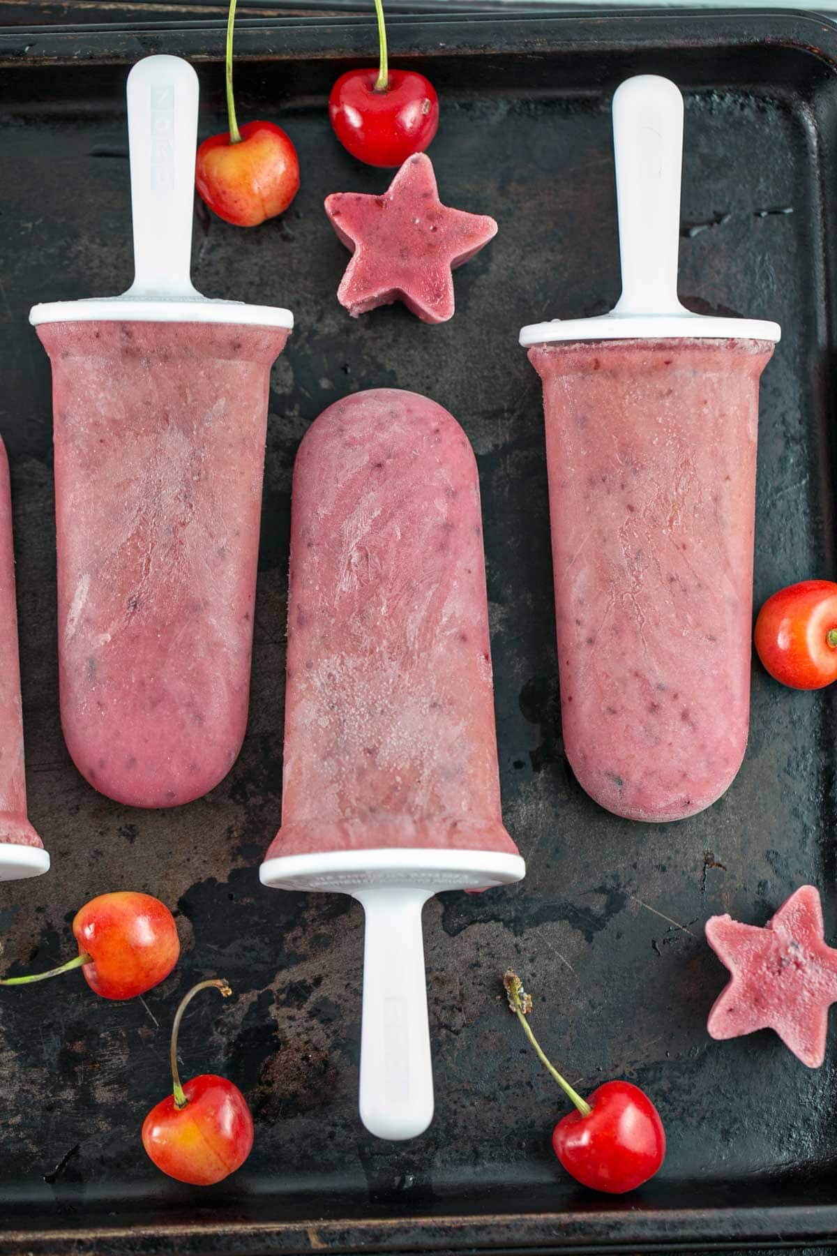 closeup view of watermelon cherry popsicles surrounded by fresh cherries