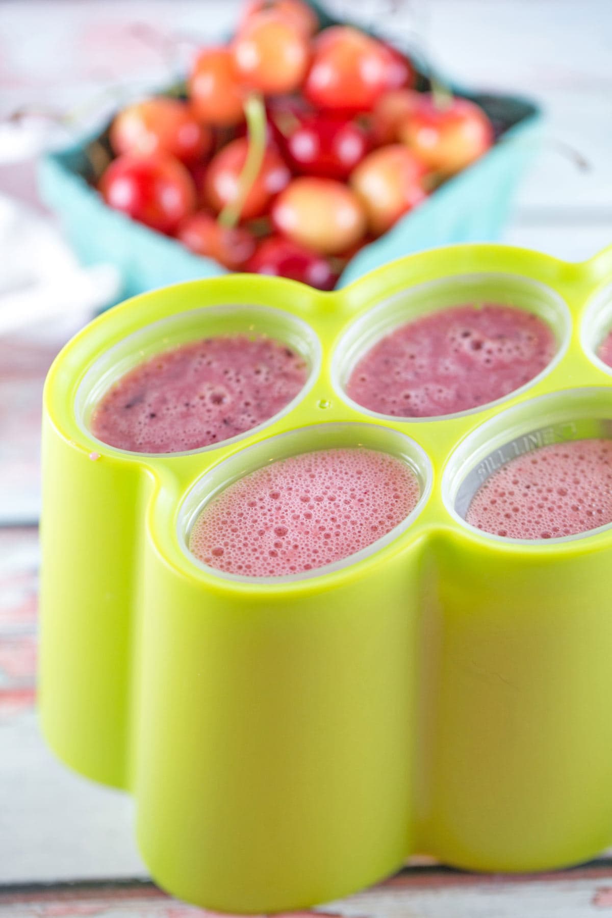 popsicle molds filled with a watermelon, cherry, and yogurt mixture