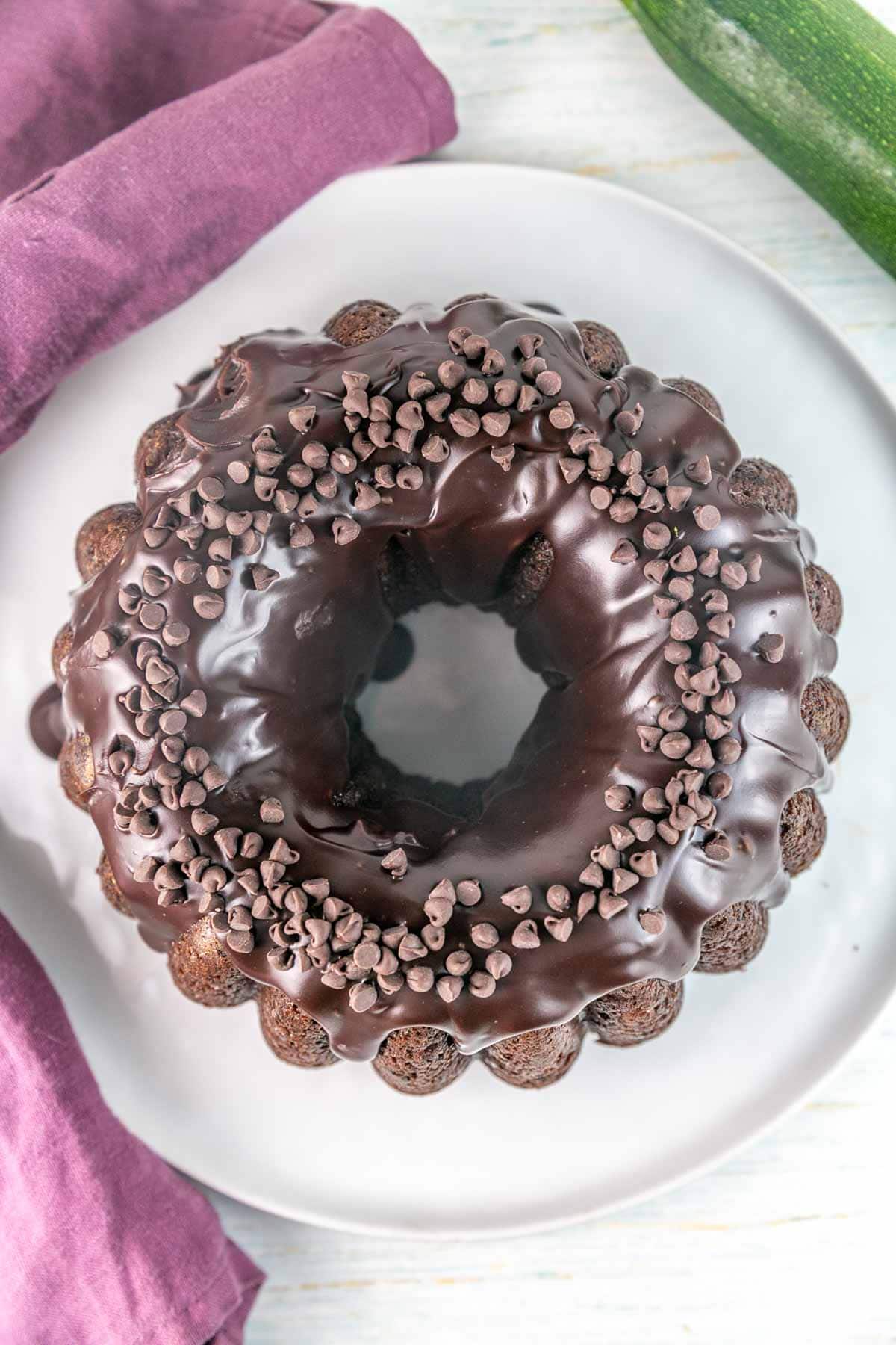 Overhead shot of zucchini bundt cake with chocolate ganache and chocolate chips on top.