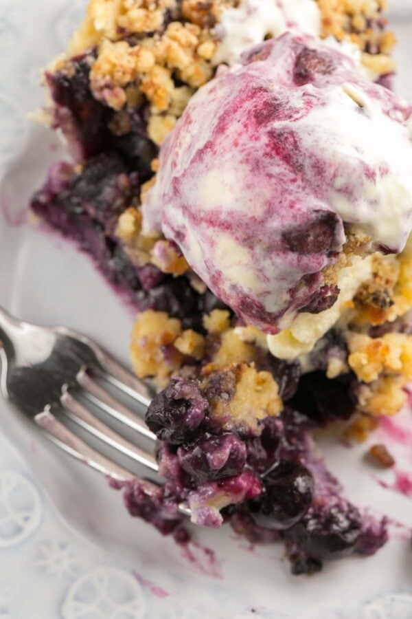 close up view of a forkful of blueberry pie full of fresh blueberries
