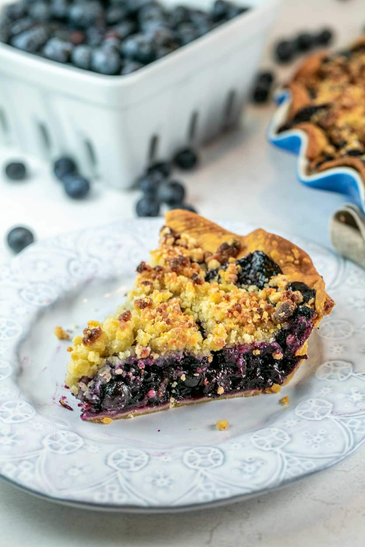 neatly cut slice of blueberry pie covered in a toasted almond crumb