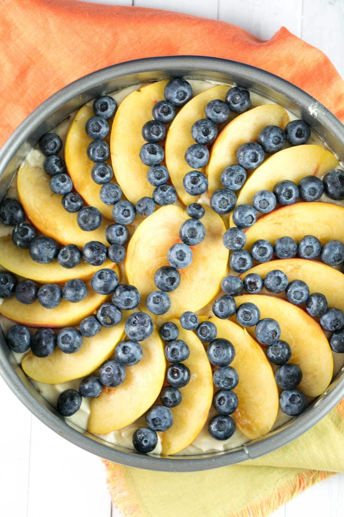 peaches and blueberries arranged on top of vanilla coffee cake batter