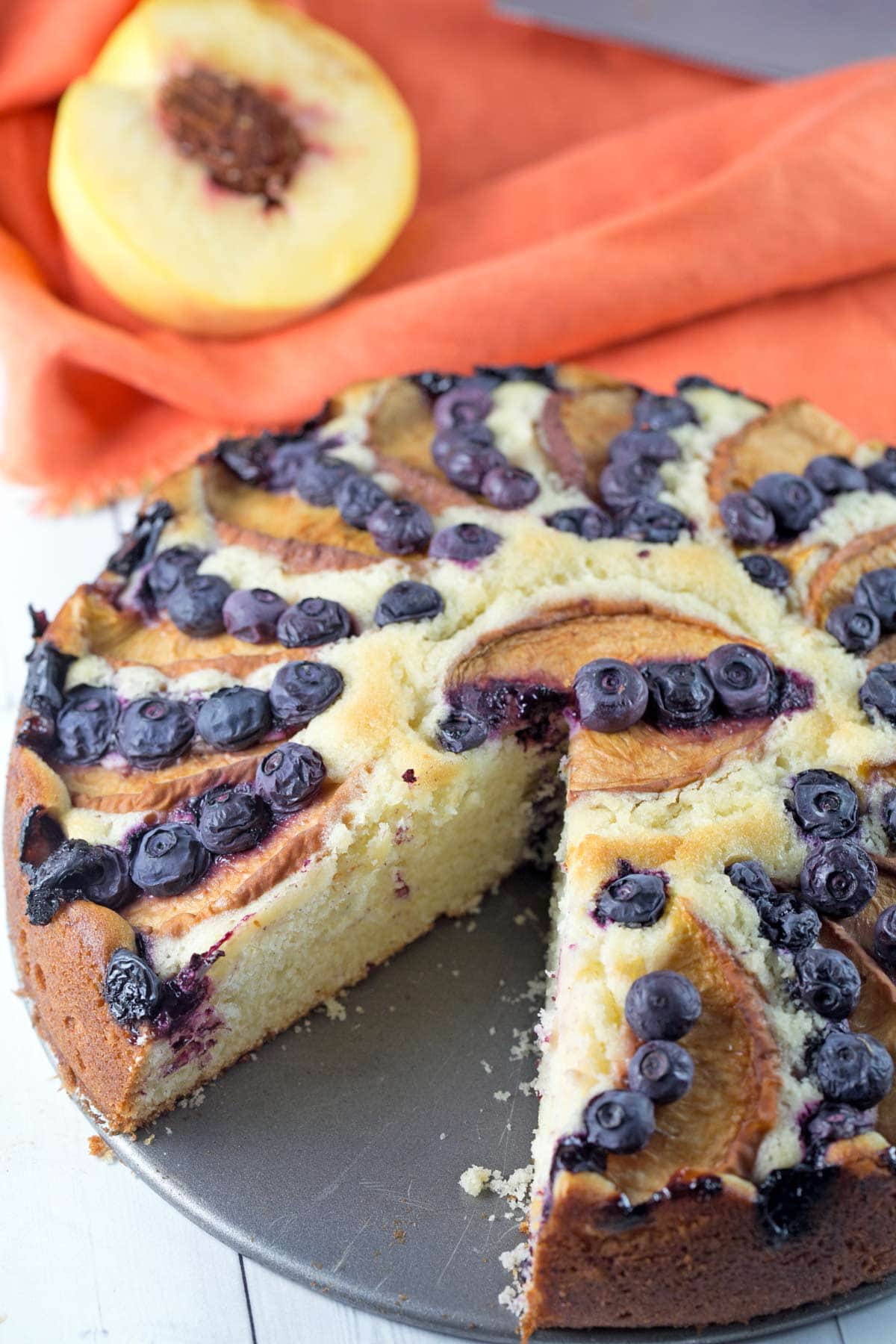 side view of a summery fruit coffee cake with one slice removed