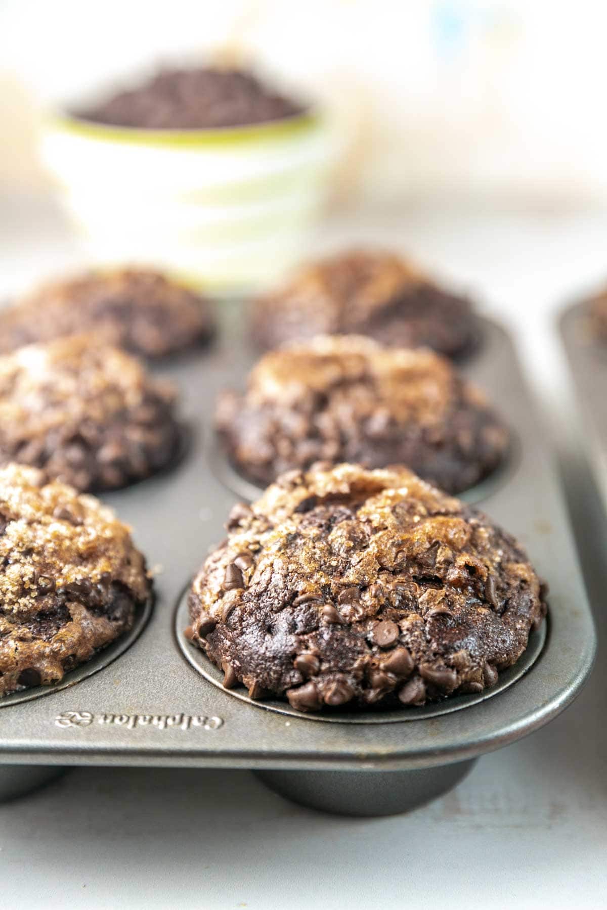 side view of domed muffins topped with streusel towering over the side of a muffin tin