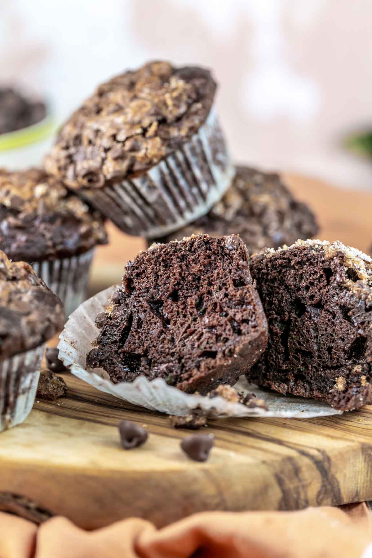stack of chocolate zucchini muffins with one muffin cut open to show the dark chocolatey interior