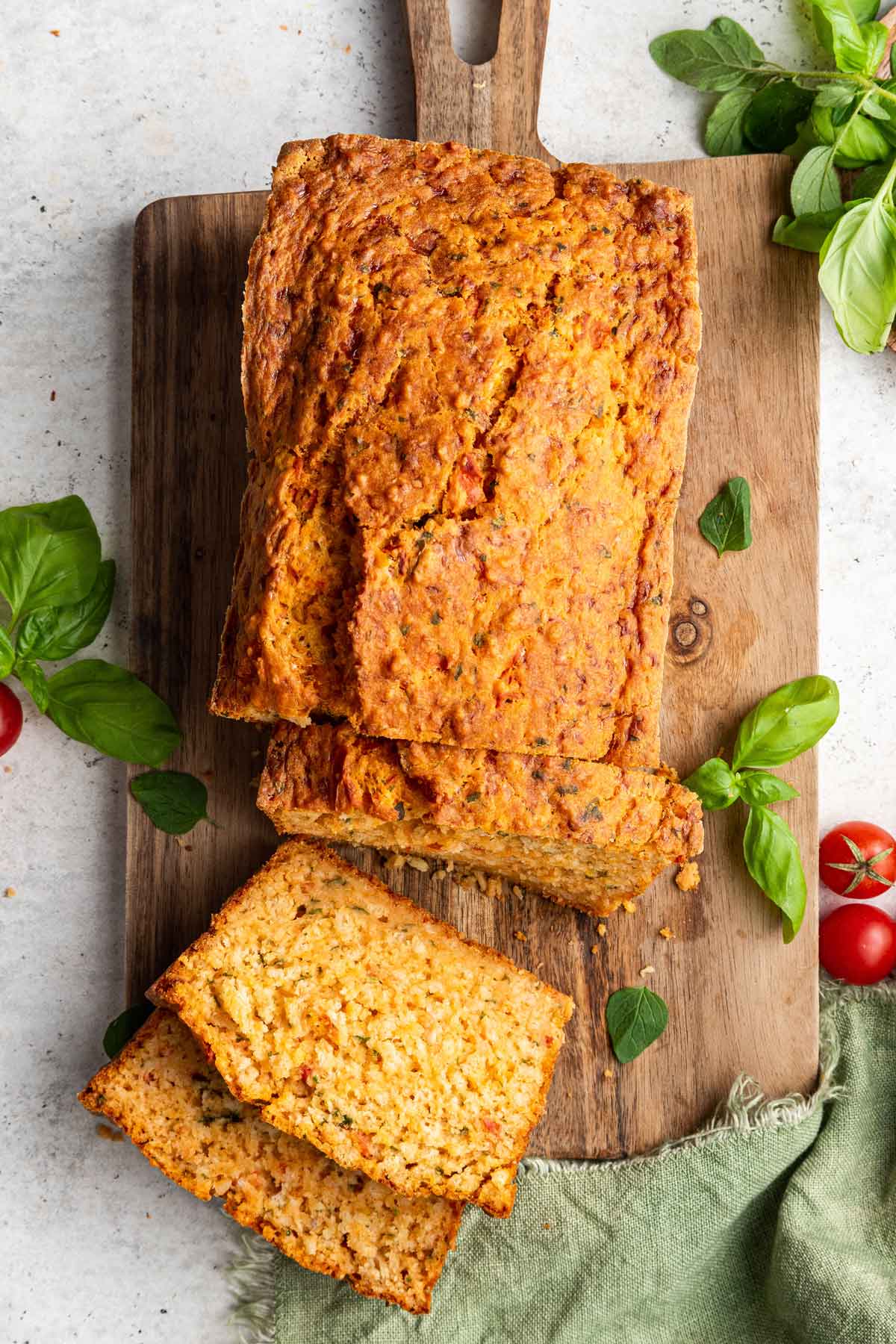 overhead view of a loaf of tomato bread with a few slices on a cutting board