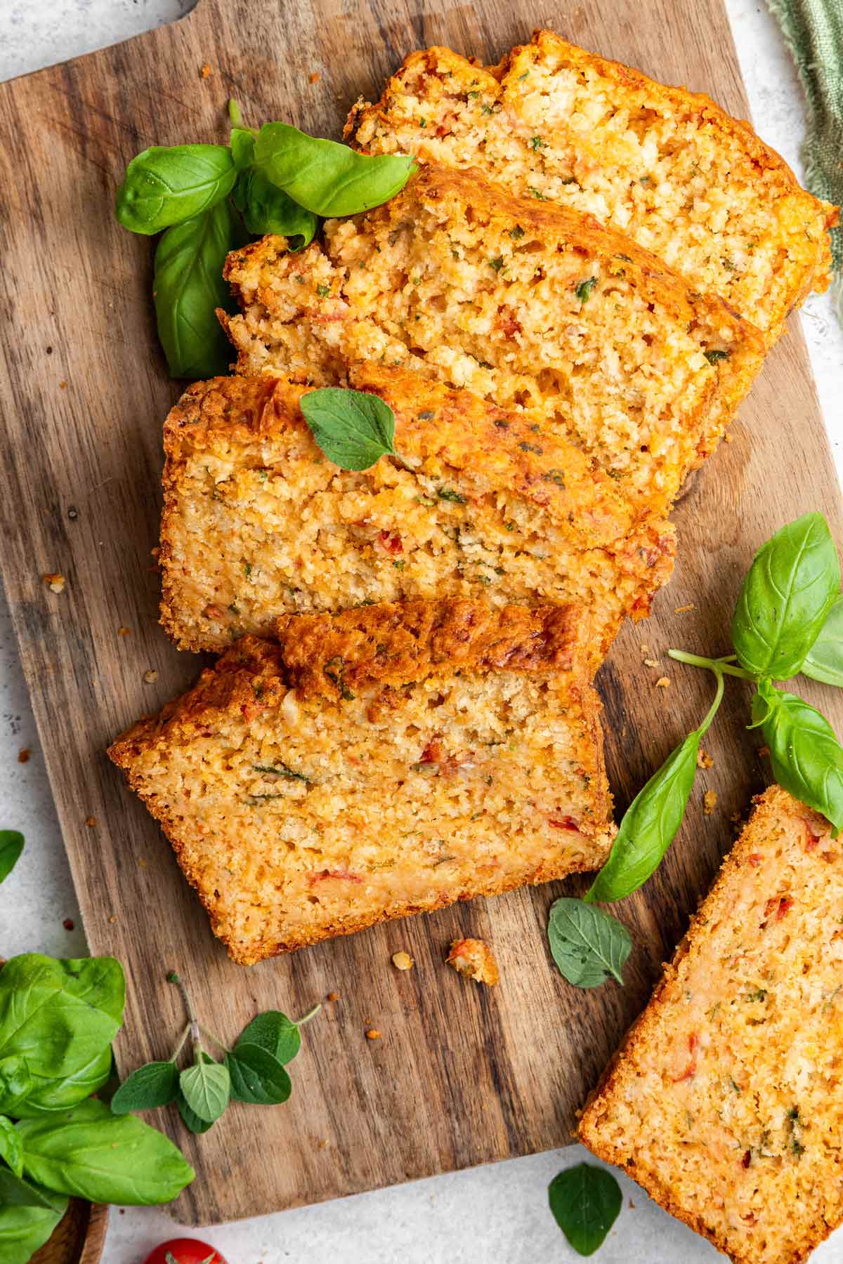 slices of bread flecked with tomato and basil on a wooden cutting board