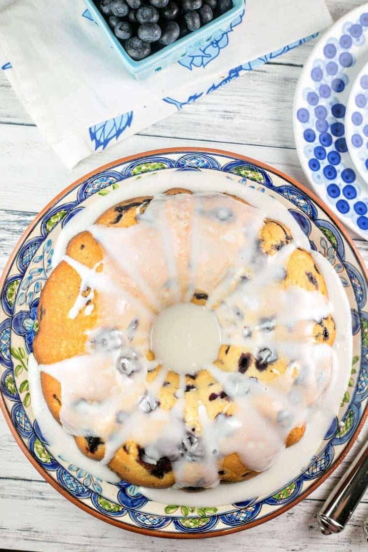 blueberry bundt cake with lemon glaze on a decorative blue serving plate