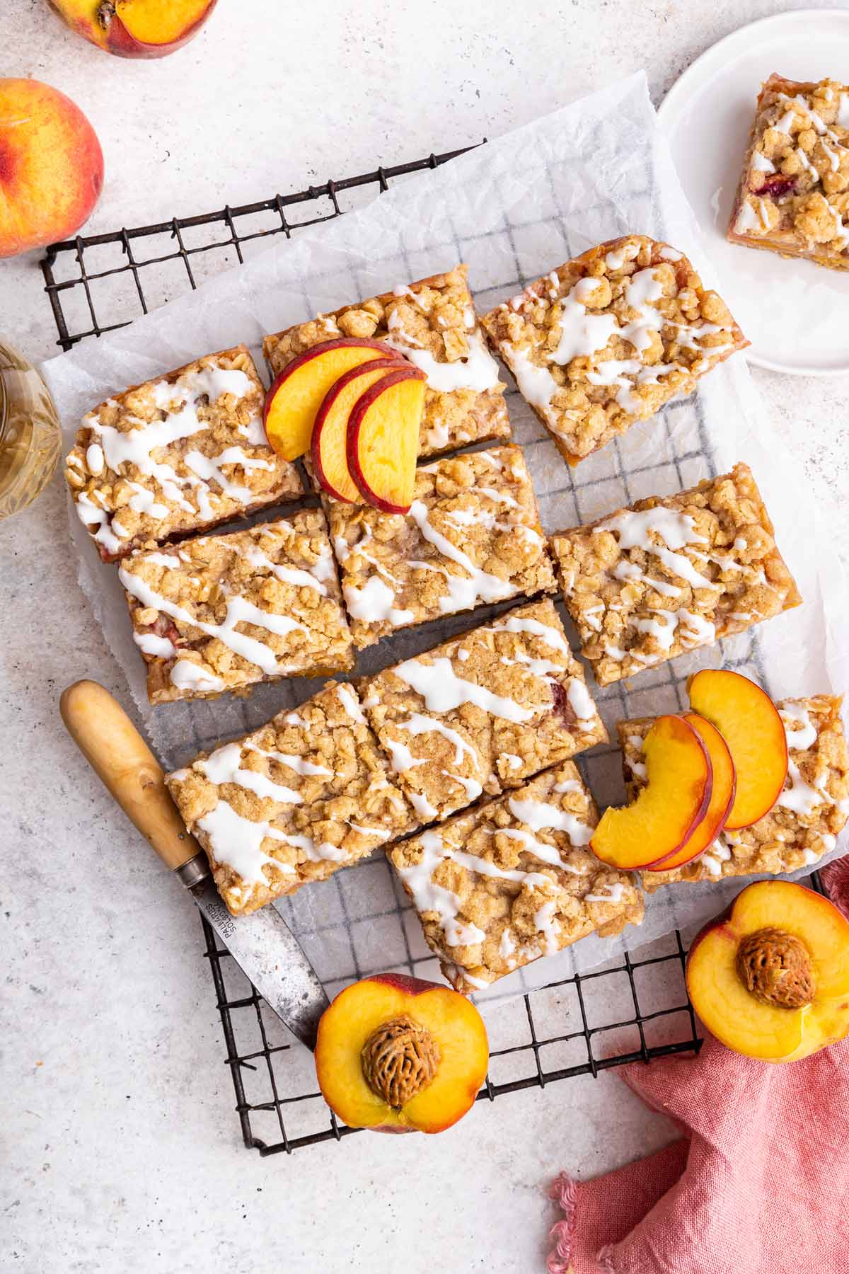 peach pie bars with a sugar glaze cut into squares and arranged on a cooling rack