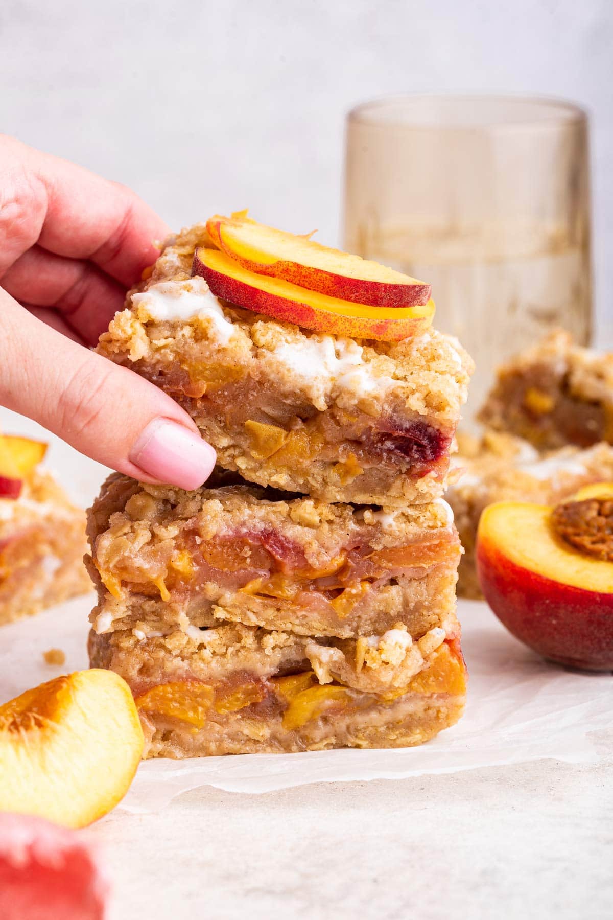 stack of three peach pie bars with a hand reaching towards the top bar