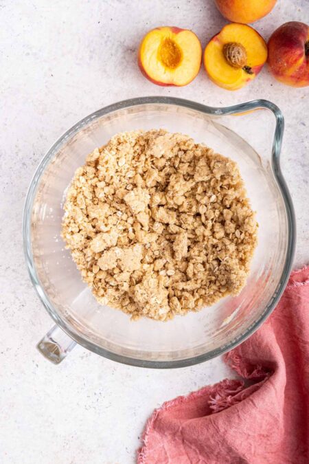 cutting butter into a flour and oat mixture to make a pie bar crust