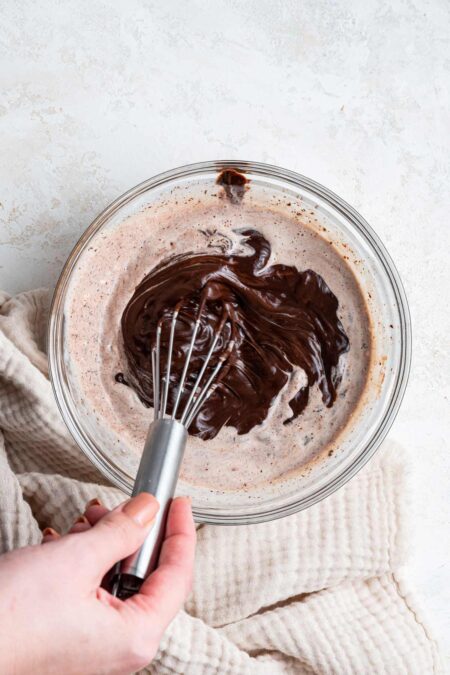 hand holding a whisk stirring together chocolate ganache