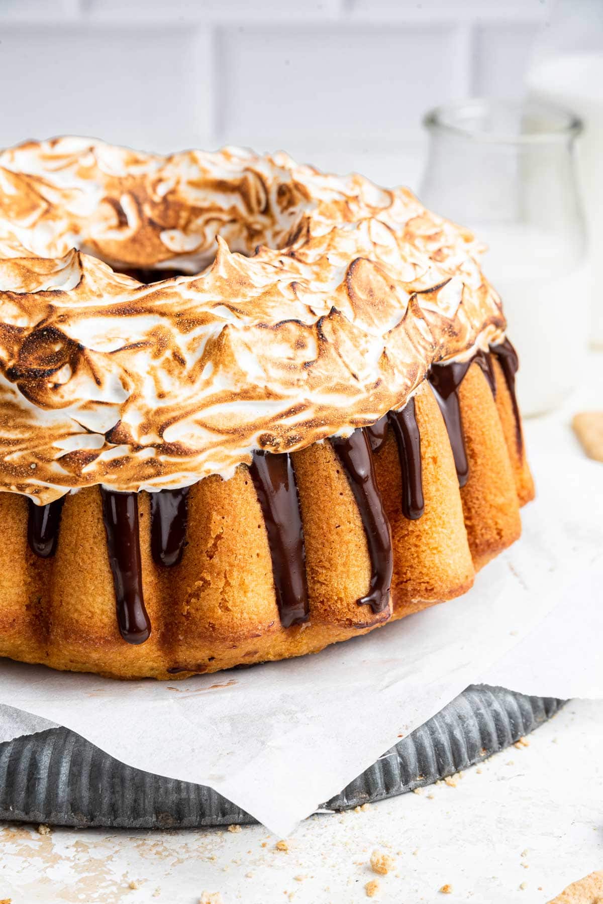 graham cracker bundt cake covered with chocolate ganache and a fluffy pile of marshmallow frosting