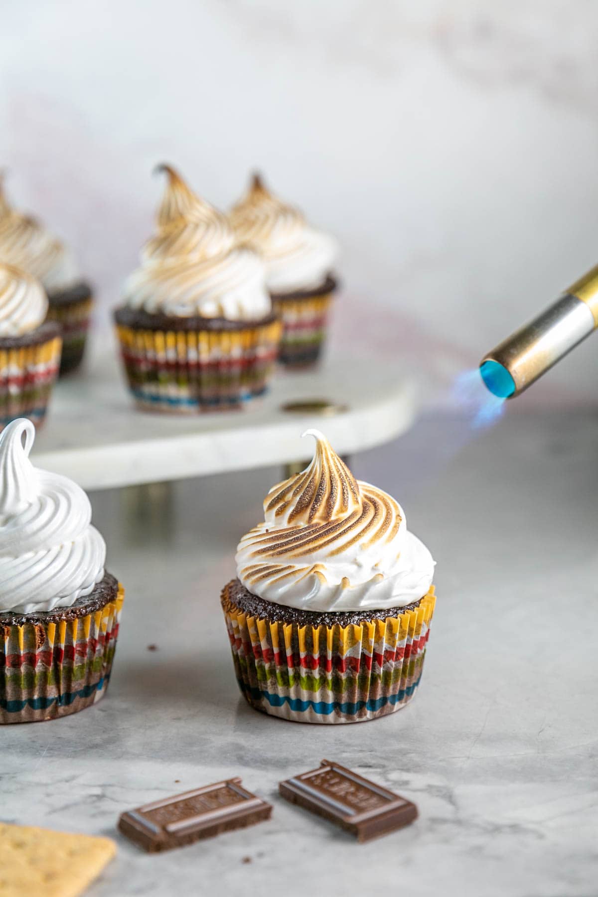 Kitchen torch toasting the top of a s'mores cupcake. 