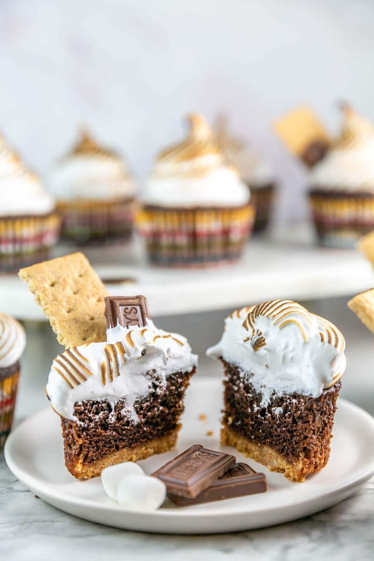 s'mores cupcake cut in half to show the graham cracker crust and fluffy meringue frosting