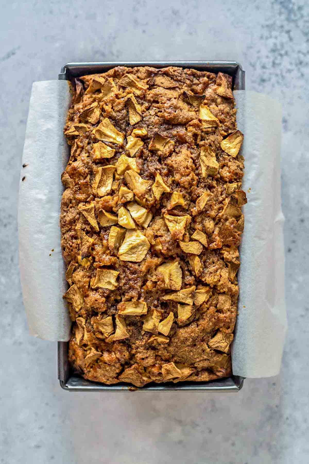 loaf of freshly baked apple bread in a loaf pan.