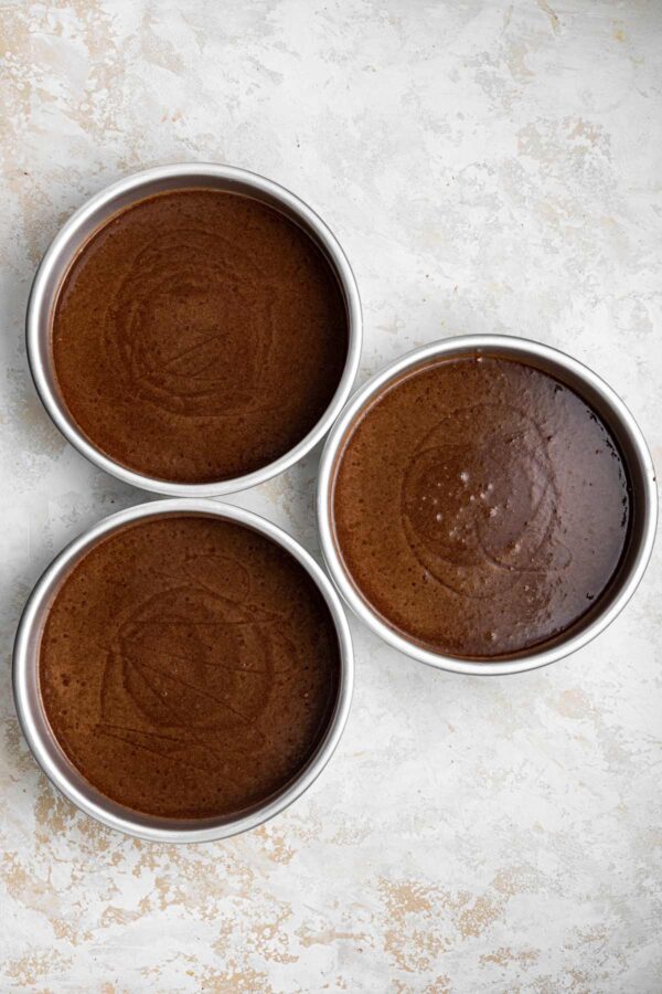 three cake pans filled with chocolate cake batter.