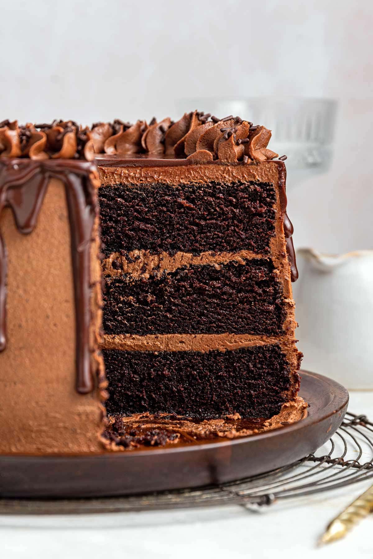 side view of a cut slice of a three layer chocolate cake showing the thick dark chocolate cake layers.