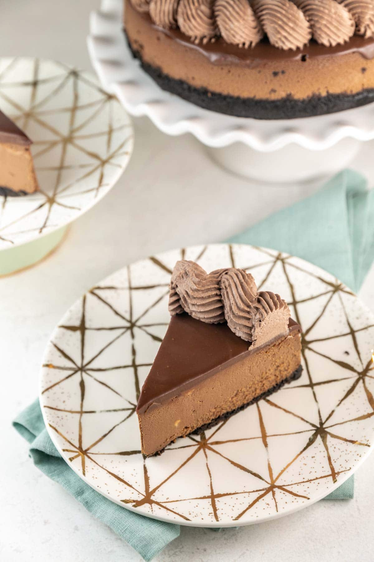 large slice of chocolate cheesecake on a decorative dessert plate.