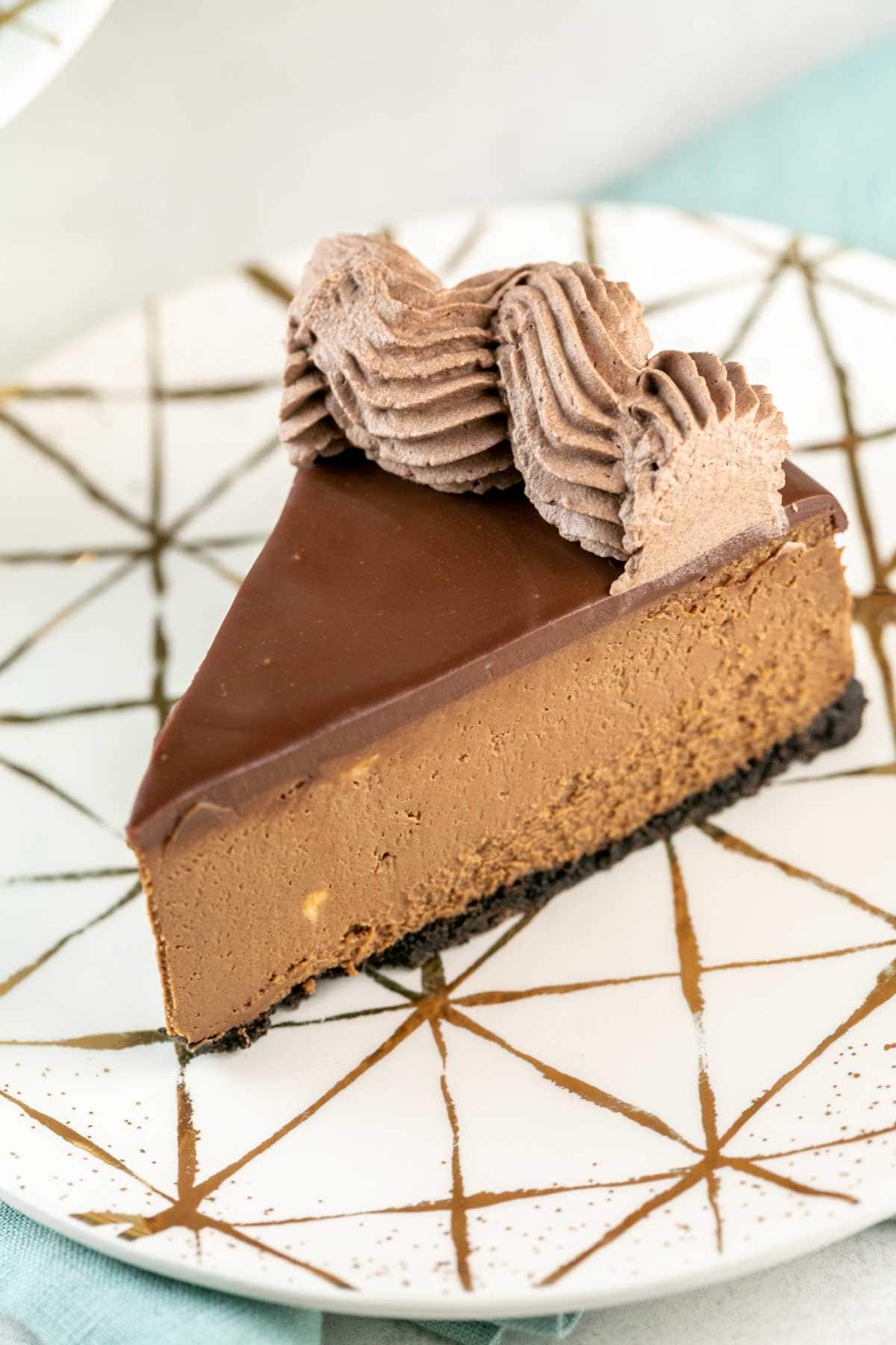 single slice of chocolate cheescake covered in ganache and ganache frosting.