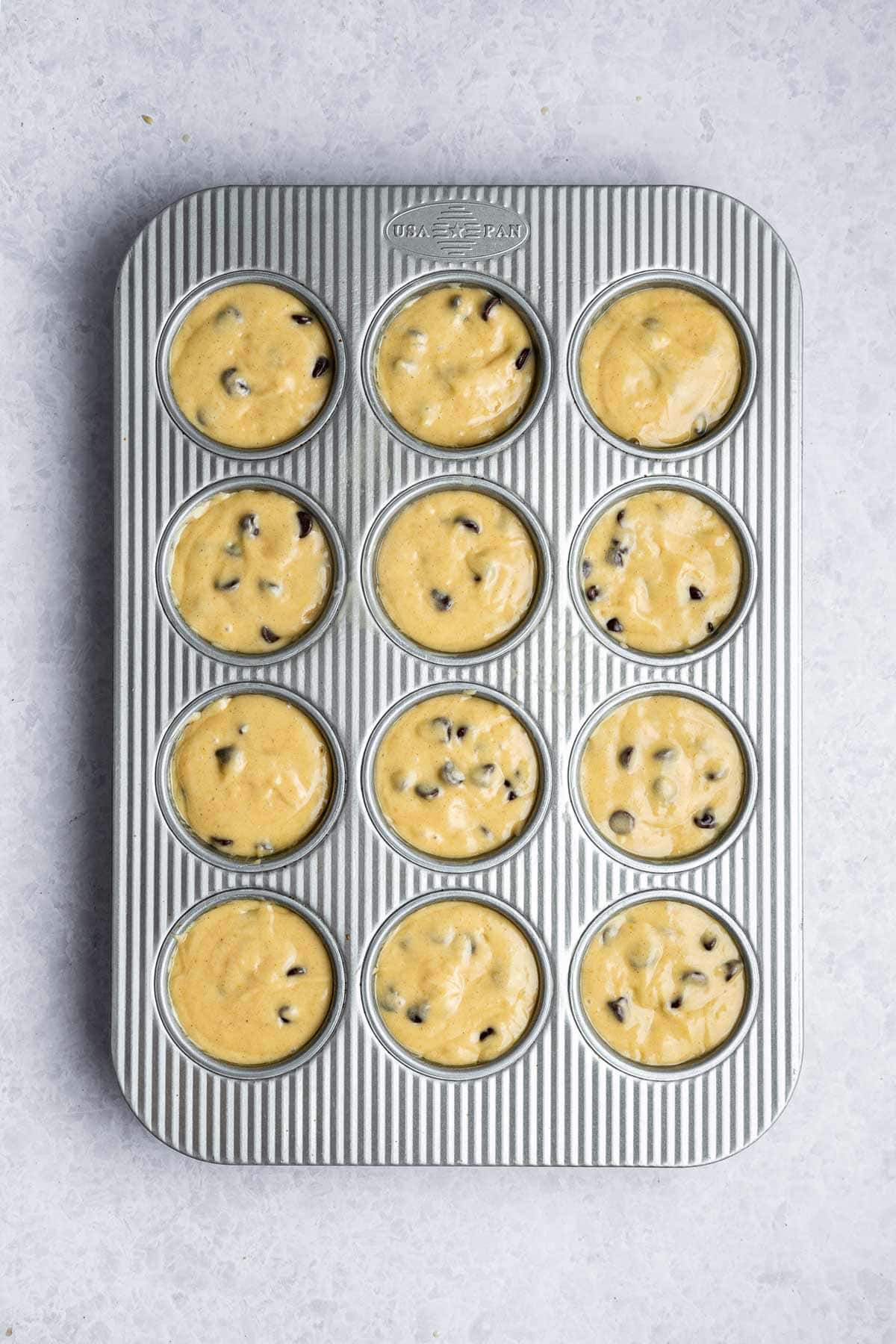 unbaked muffin batter filled to the top of a muffin tin.