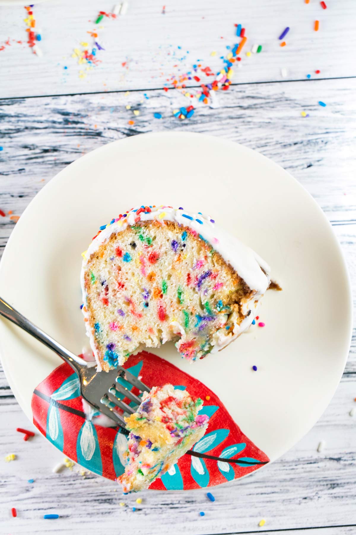 slice of colorful funfetti bundt cake on its side with one forkful removed.