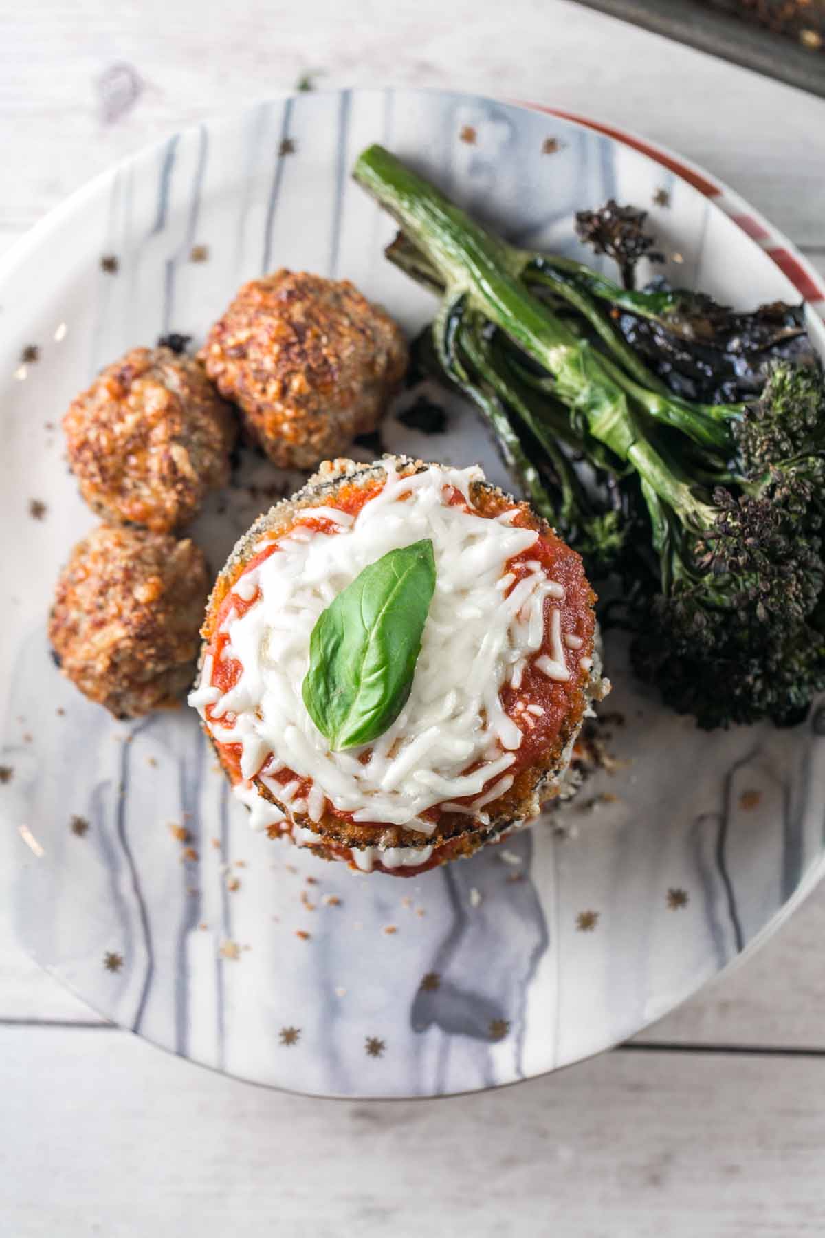 overhead view of baked eggplant parmesan stacks on decorative marble plates