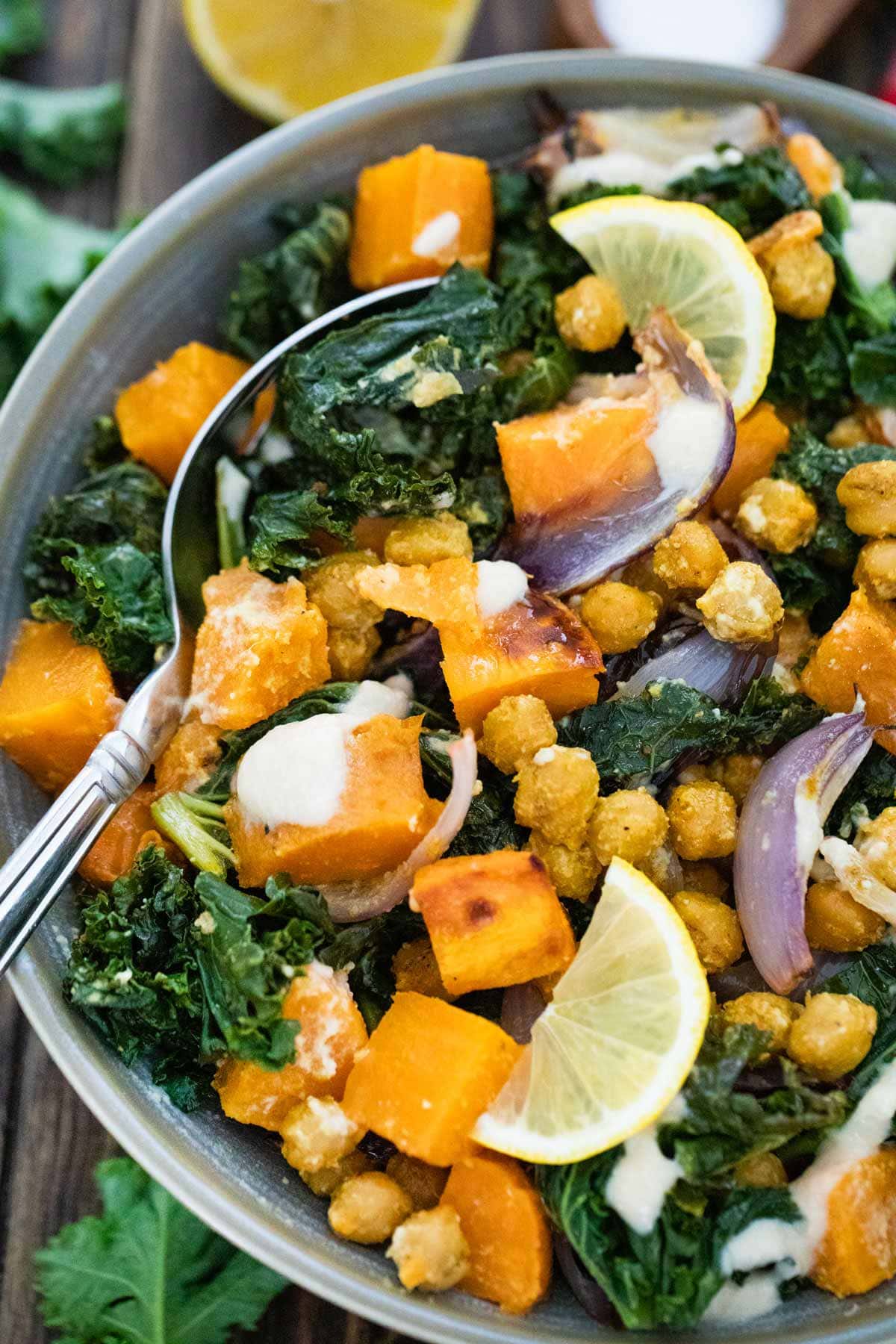 vegan buddha bowl filled with kale and sweet potatoes with a large serving spoon.