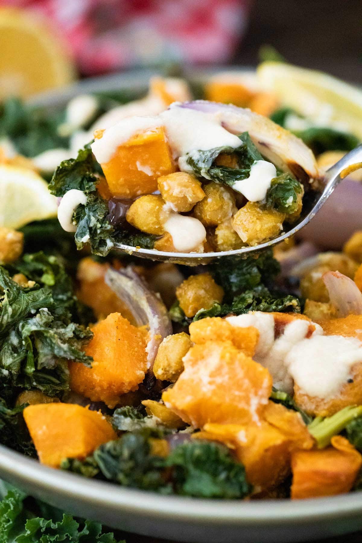 spoon scooping up chickpeas and sweet potatoes covered in a tahini sauce.