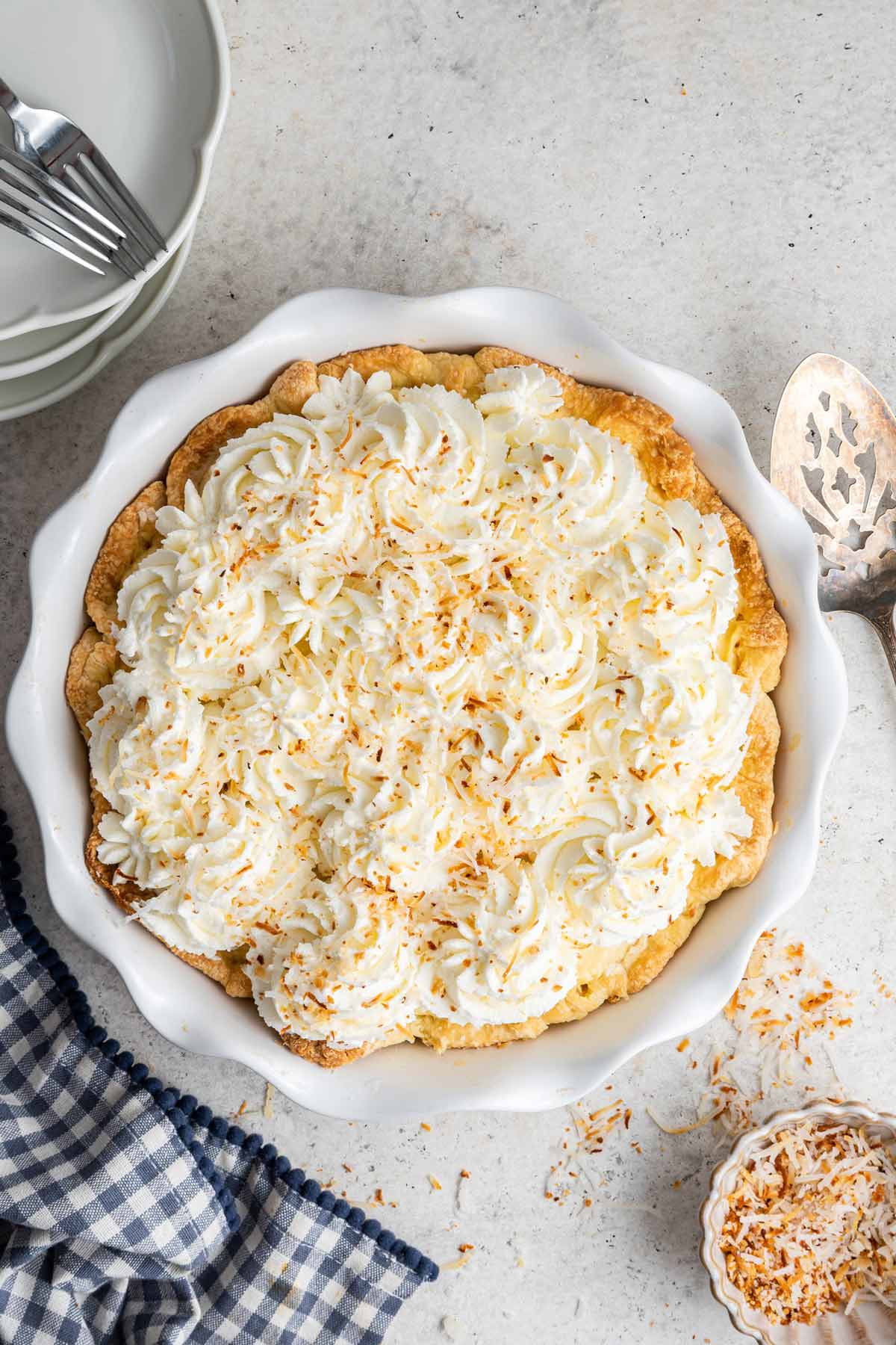 pie covered with swirls of fluffy whipped cream and sprinkled with toasted coconut.