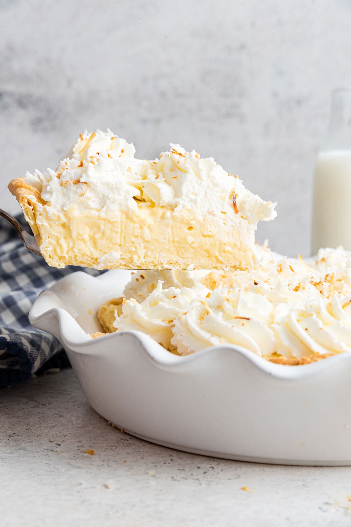 side view of a slice of coconut cream pie being lifted out of the pie dish.