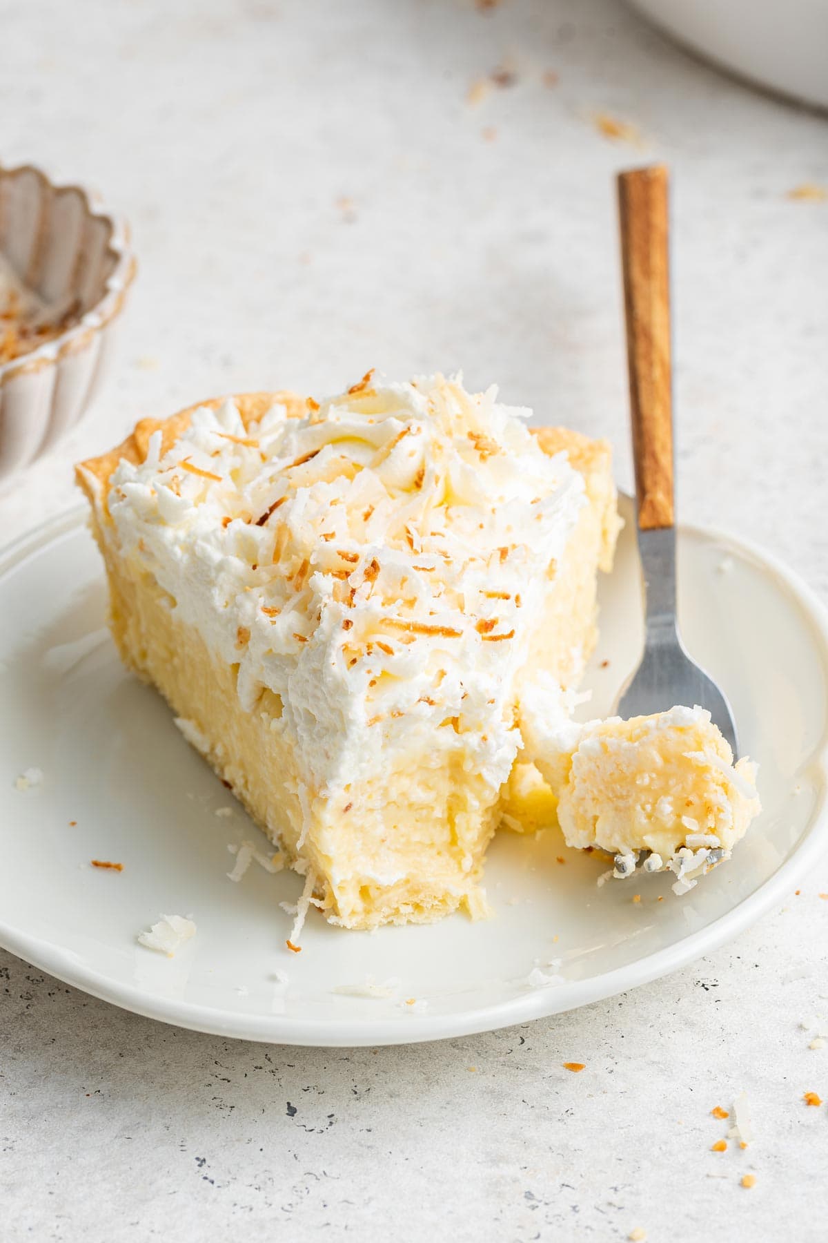 slice of coconut cream pie with one forkful removed.