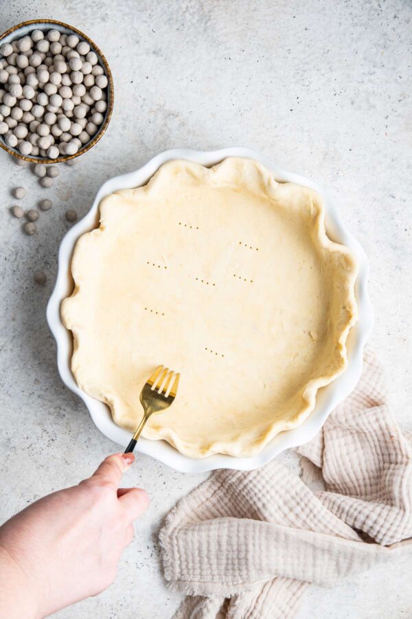 pie crust in a pie dish with a fork poking holes along the bottom.