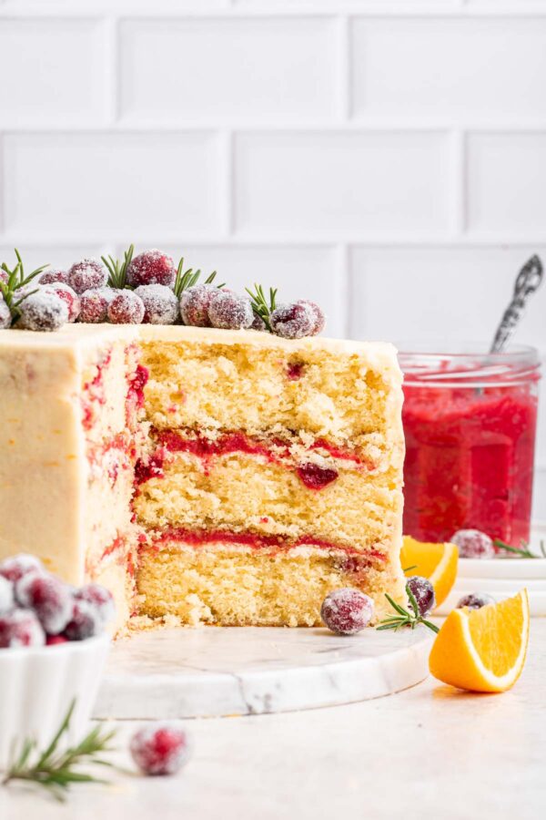 cake filled with layers of cranberry curd with a jar of curd in the background.