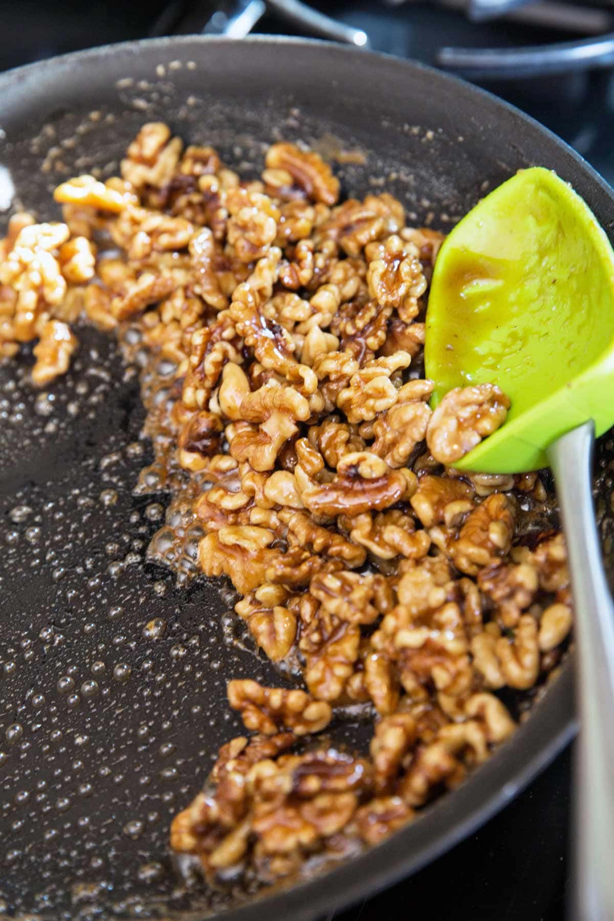 skillet filled with walnuts covered in maple syrup.