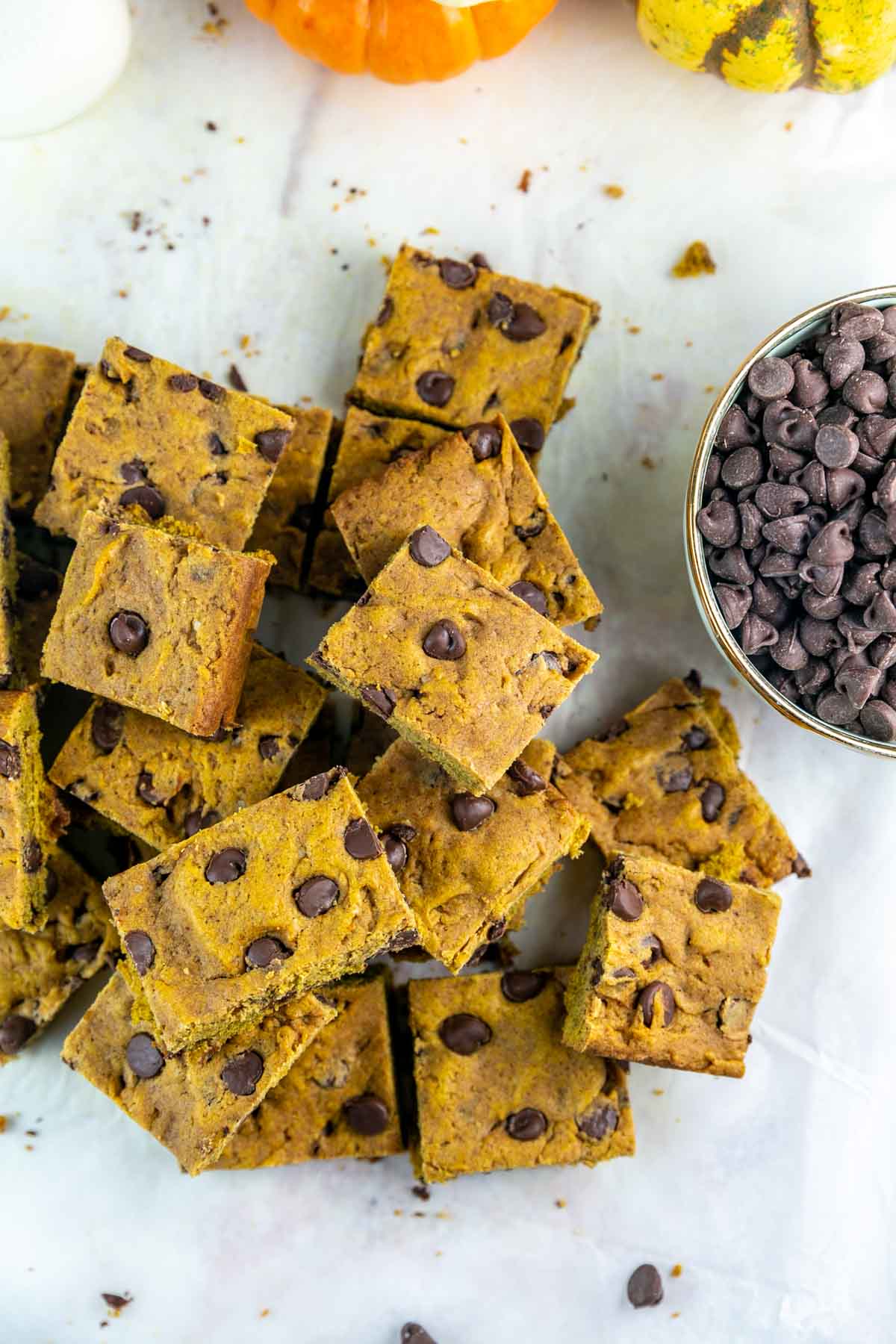 pile of pumpkin cookie bars next to a bowl of chocolate chips.