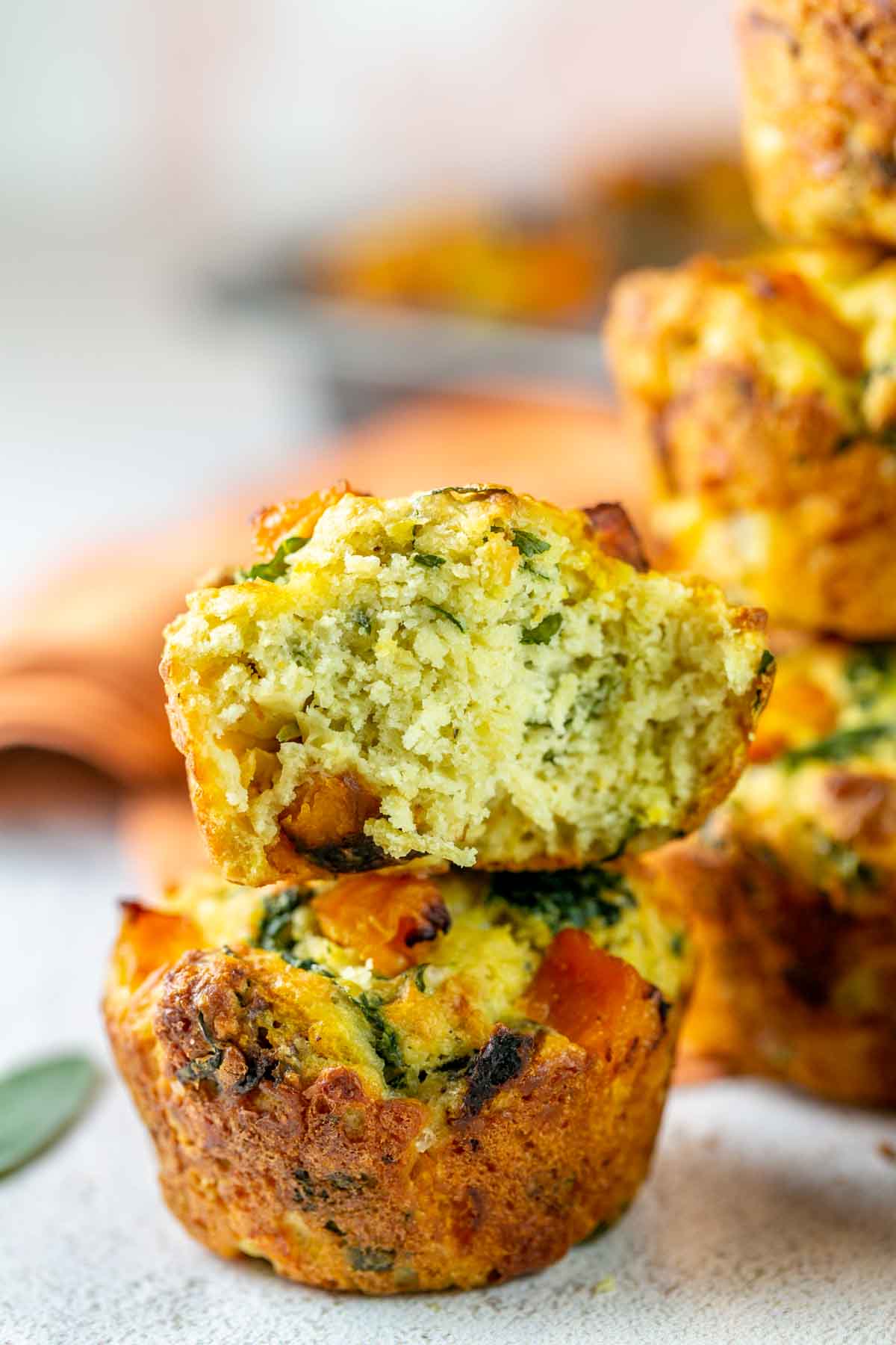 a half of a muffin stacked on top of a whole muffin showing the tight crumb and kale insisde.