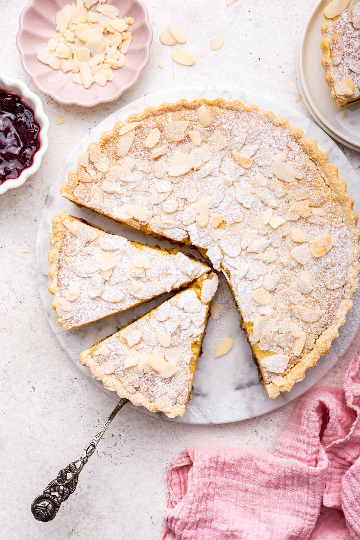 overhead view of a bakewell tart on a circular marble cake stand.