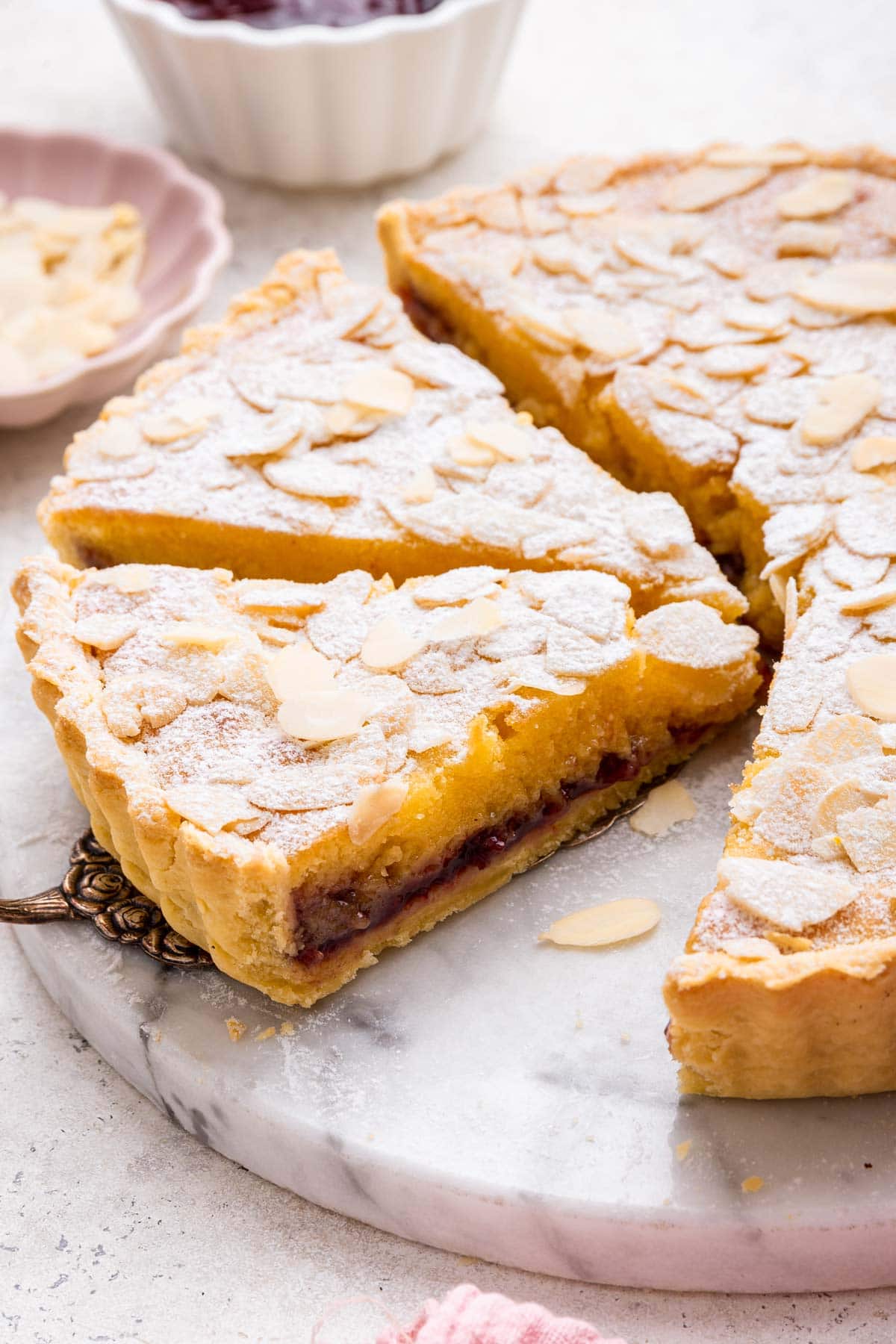 side view of a slice of bakwell tart filled with cherry jam.