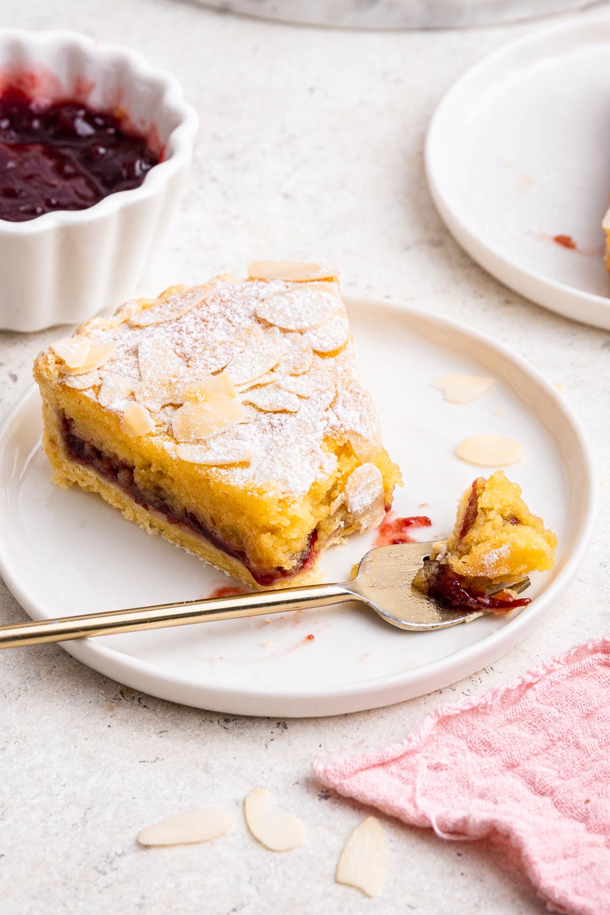 slice of bakewell tart on a dessert plate with one forkful removed.